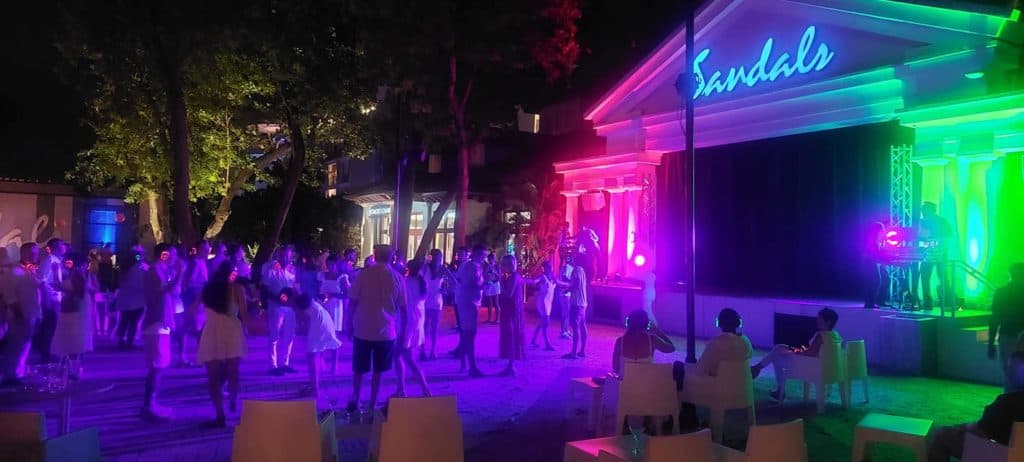 Couples dancing on an outdoor stage at the Silent Disco at Sandals Royal Barbados, enjoying a romantic and lively atmosphere under the night sky.