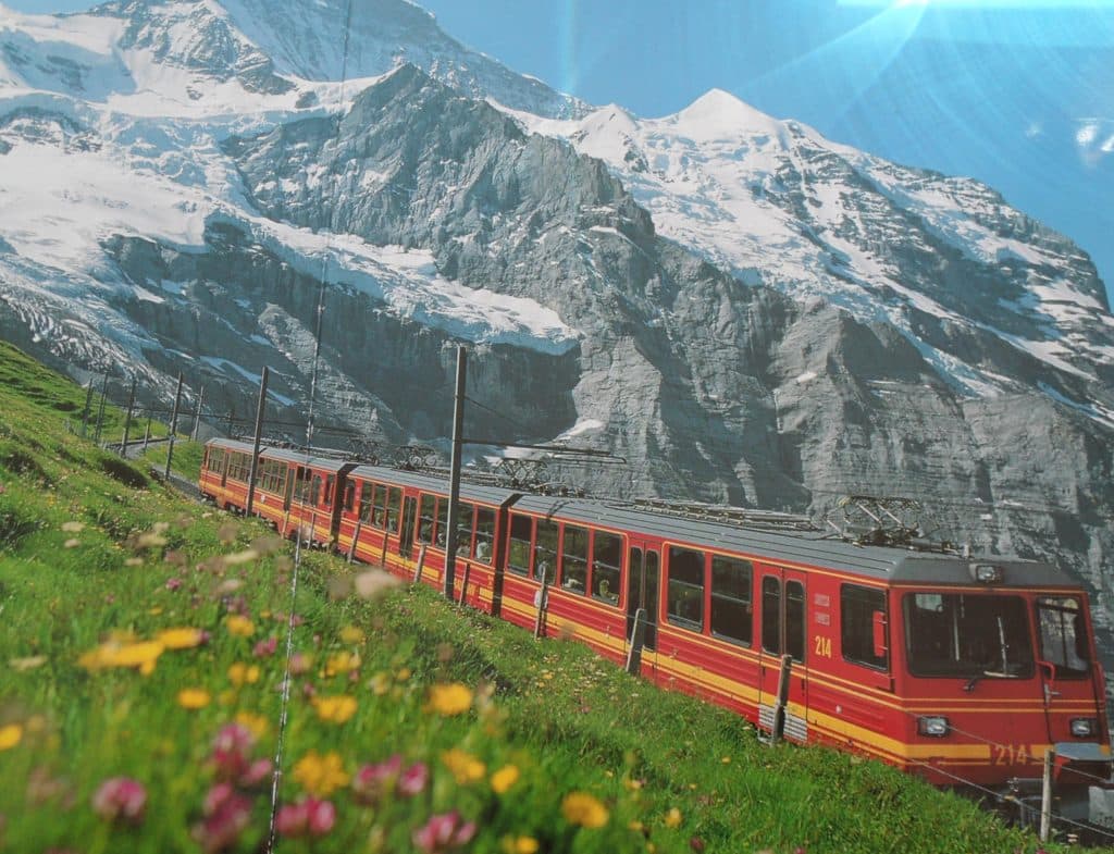 Red train luxury Swiss adventure to Jungfraujoch amidst stunning mountains.