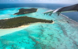 A stunning aerial view of The Brando resort showcasing the islands of the atoll with the tip of a jet wing in the picture.