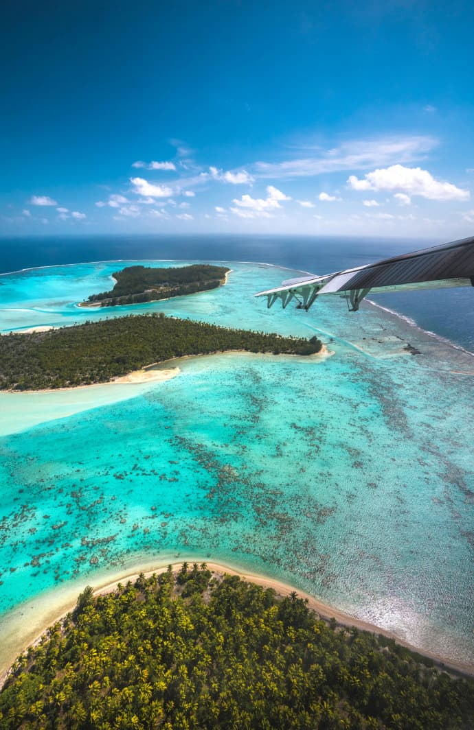 A stunning aerial view of The Brando resort showcasing the islands of the atoll with the tip of a jet wing in the picture.