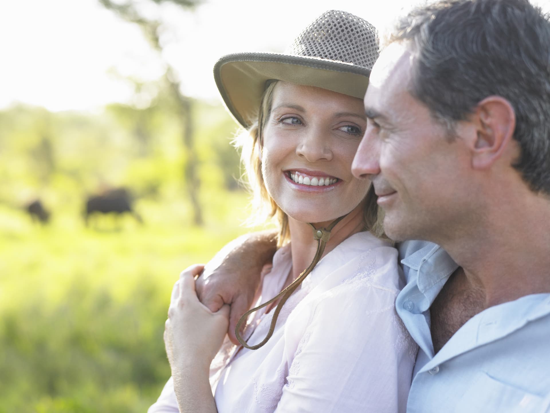 Happy couple enjoying a moment on African safaris with greenery and an unknown animal in the background