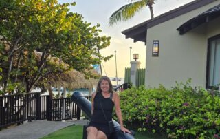 Sheila Cannon at Sandals Grande St. Lucian sitting on a cannon at sunset in front of the Grande Rondovals