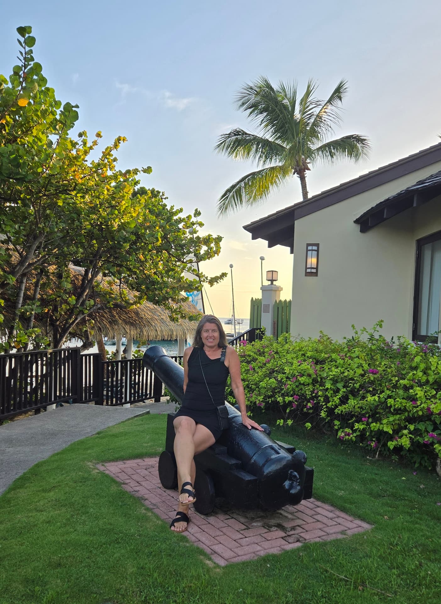 Sheila Cannon at Sandals Grande St. Lucian sitting on a cannon at sunset in front of the Grande Rondovals