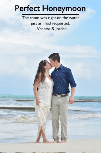 Couple kissing on the beach during their perfect honeymoon, planned by Sheila Cannon, with their bare feet in the sand and the ocean in the background.