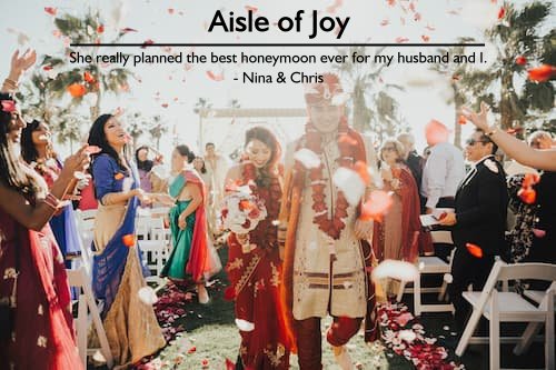 Couple in traditional clothing at their Indian wedding, with guests throwing rose petals, showcasing Sheila's perfect honeymoon planning.