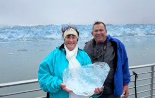 Lucia holding a chunk of glacial ice in front of Hubbard Glacier during the Alaska cruise adventure.