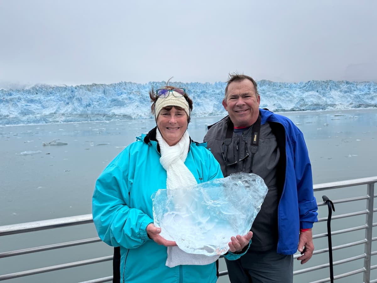 Lucia holding a chunk of glacial ice in front of Hubbard Glacier during the Alaska cruise adventure.