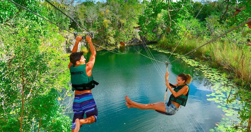 Couple ziplining into a cenote on the Xenotes Tour included with a stay at Hotel Xcaret Mexico.